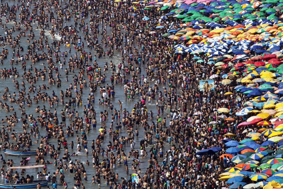 In this Jan. 20, 2013 photo, people wade on the shoreline of Agua Dulce beach, in Lima, Peru. While Lima's elite spends its summer weekends in gate beach enclaves south of the Peruvian capital, the working class jams by the thousands on a single municipal beach of grayish-brown sands and gentle waves. The only barrier to entry to Agua Dulce beach is two dollars, the price of bus fare to get there and home. (AP Photo/Rodrigo Abd)