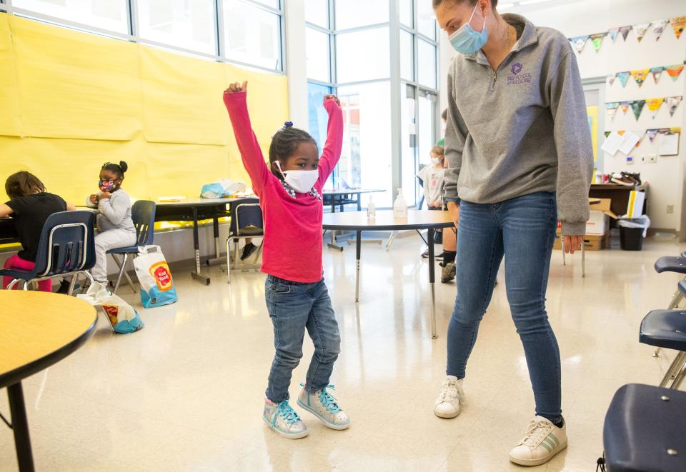 Ni'lisa Owens, 5, a kindergartner at Enos Elementary School, celebrates with Alex Kissel, a second-year medical student at the SIU School of Medicine, after getting a new pair of shoes through SIU's participation in the national "Shoes That Fit" program at the elementary school Thursday. More than 85 students at McClernand and Enos elementary school received shoes and socks through funds raised by SIU Medical students. [Justin L. Fowler/The State Journal-Register]