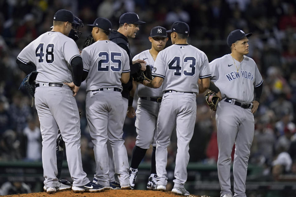 New York Yankees manager Aaron Boone, middle, hands the ball and speaks with New York Yankees relief pitcher Jonathan Loaisiga (43) in the sixth inning of an American League Wild Card playoff baseball game at Fenway Park, Tuesday, Oct. 5, 2021, in Boston. (AP Photo/Charles Krupa)