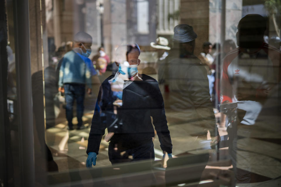 South African civil servants assist informal vendors to receive temporary working licenses, at the entrance of a municipal office building, in Johannesburg, Tuesday, April 7, 2020. South Africa and more than half of Africa's 54 countries have imposed lockdowns, curfews, travel bans or other restrictions to try to contain the spread of COVID-19. (AP Photo/Jerome Delay)