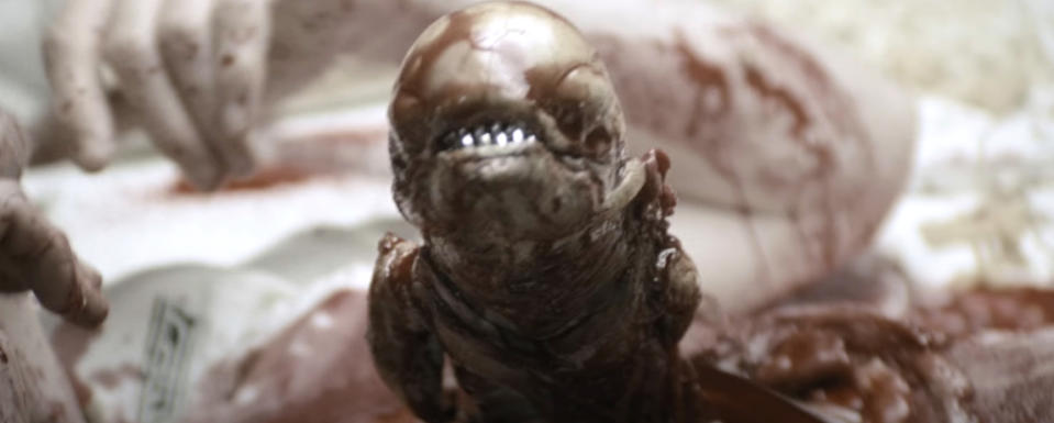 Alien character from the movie "Alien" appears emerging from a host, showcasing its teeth and otherworldly features