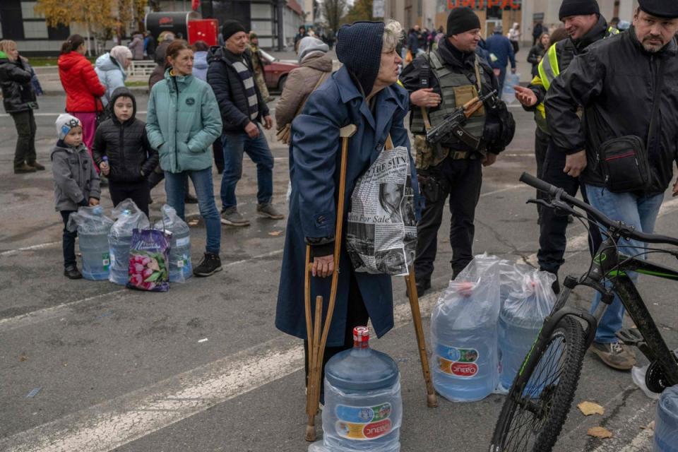 A disabled woman waits for help to carry her water during an aid supply distribution in the centre of Kherson (AFP/Getty)