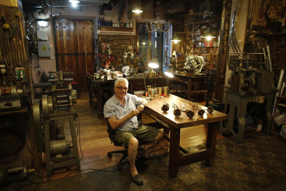 Juan Carlos Pallarols, 74, posses with roses made with spent munitions from the Falklands war, at his studio in Buenos Aires, Argentina, Wednesday, Jan. 25, 2017. Pallarols, an Argentine goldsmith known for crafting the presidential batons, collects old ammunition from the 1982 Falklands war to craft roses which he will send to the Argentine and British war cemeteries in the islands in an effort to build a bridge of peace and understanding between the nations. (AP Photo/Victor R. Caivano)