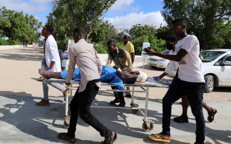 Civilians at Madina hospital assist an injured man after a minibus struck a roadside bomb at Hawa Abdi village, northwest of Mogadishu