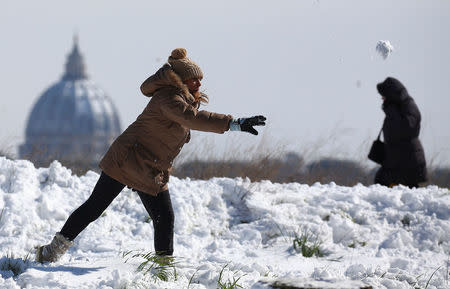 A woman throws a snowball as Saint Peter's Basilica dome is seen in the background after heavy snowfall in Rome. REUTERS/Alessandro Bianchi