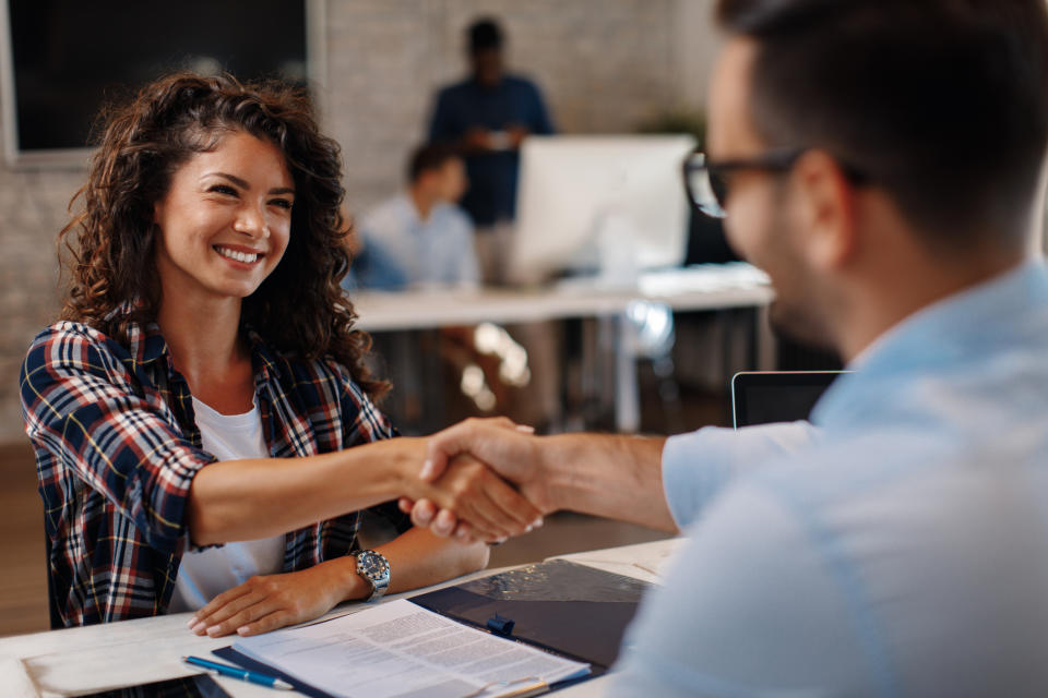 Man shaking woman's hand across a desk