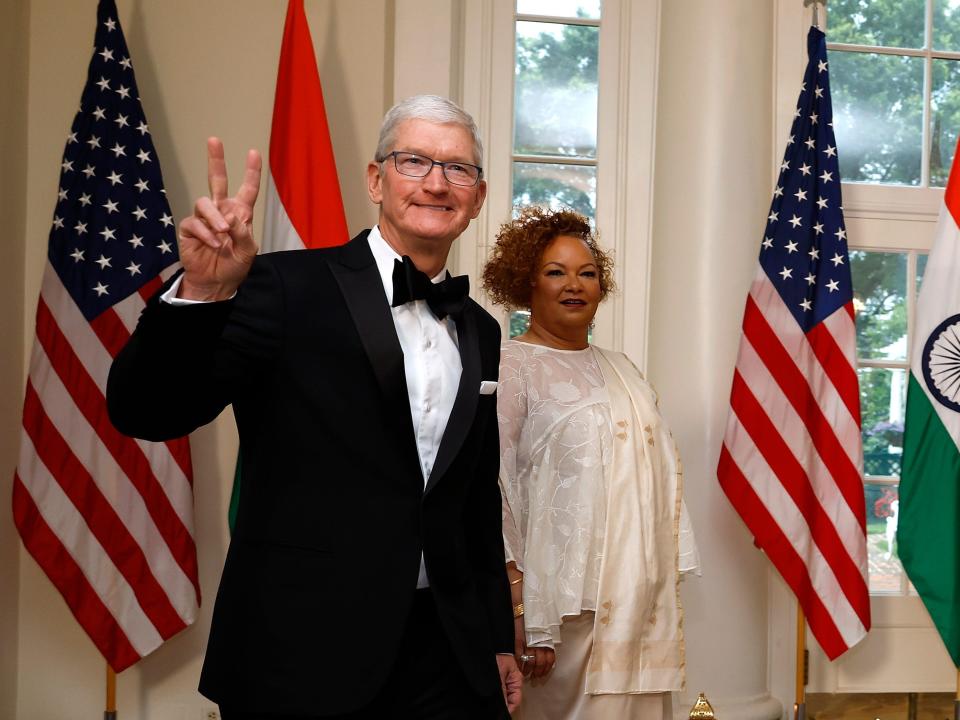 Apple CEO Time Cook holds up a peace sign, next to Apple's vice president of environment, policy, and social initiatives Lisa Jackson