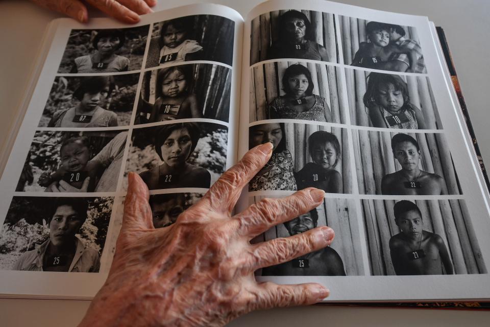 Claudia Andujar keeps a book open on a page with portraits of indigenous peopleAFP via Getty