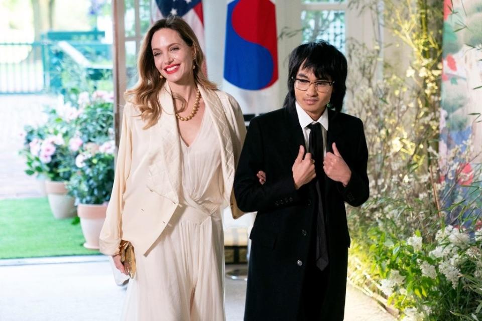 Angelina Jolie in an elegant cream dress and Zahara Jolie-Pitt in a black suit at a formal event