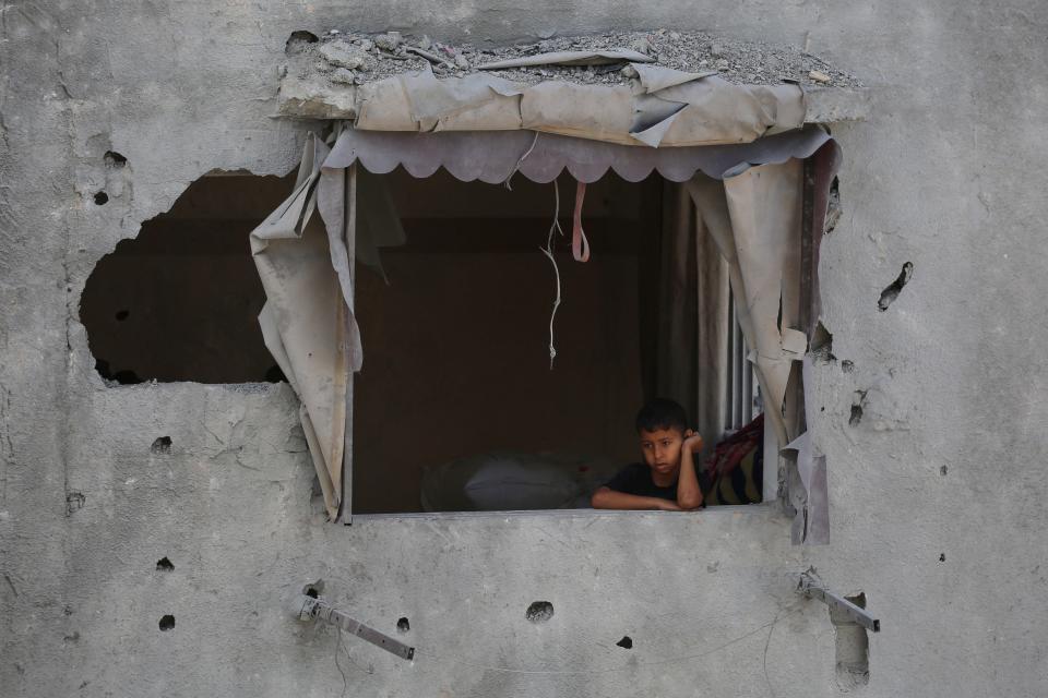 A Palestinian boy looks at the destruction from the window of a damaged house following Israeli bombardment of Rafah's Tal al-Sultan district in the southern Gaza Strip on May 7, 2024.
