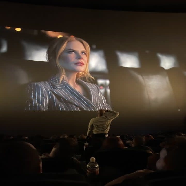 A man saluting Kidman as she appears on the big screen before the movie audience