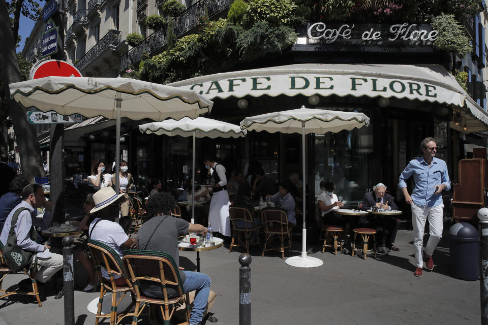 People sit on the Cafe de Flore terrace in Paris, Tuesday, June 2, 2020. Parisians who have been cooped up for months with take-out food and coffee will be able to savor their steaks tartare in the fresh air and cobbled streets of the City of Light once more, albeit in smaller numbers. (AP Photo/Christophe Ena)