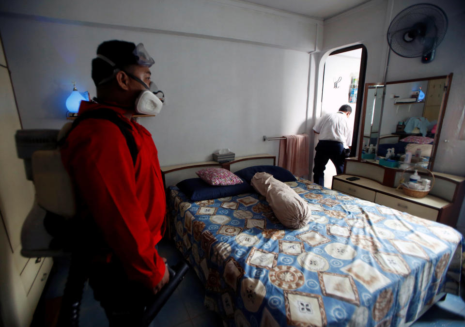 A National Environment Agency officer and a member of a pest control team checks for mosquito breeding grounds at a resident's house in a new Zika cluster area in Singapore