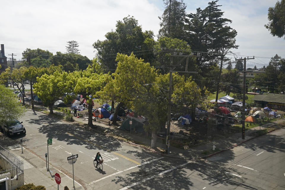 A cyclist rides past People's Park in Berkeley, Calif., on March 29, 2022. Many of the trees in the park were toppled on Aug. 3, 2022, during an attempt to start a construction project. The three-acre site's colorful history, forged from University of California, Berkeley's seizure of the land in 1968, has been thrust back into the spotlight by the school's renewed effort to pave over People's Park as part of a $312 million project that includes sorely needed housing for about 1,000 students. (AP Photo/Eric Risberg)