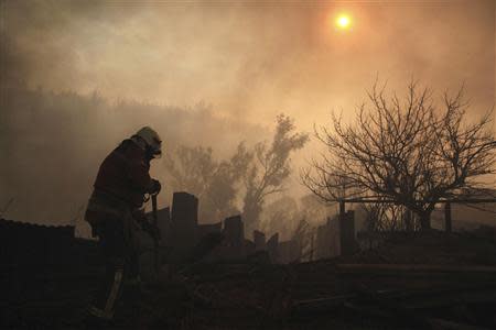 A firefighter removes the remains of a house at the location where a forest fire burned several neighbourhoods in the hills in Valparaiso city, northwest of Santiago, April 13, 2014. REUTERS/Cristobal Saavedra