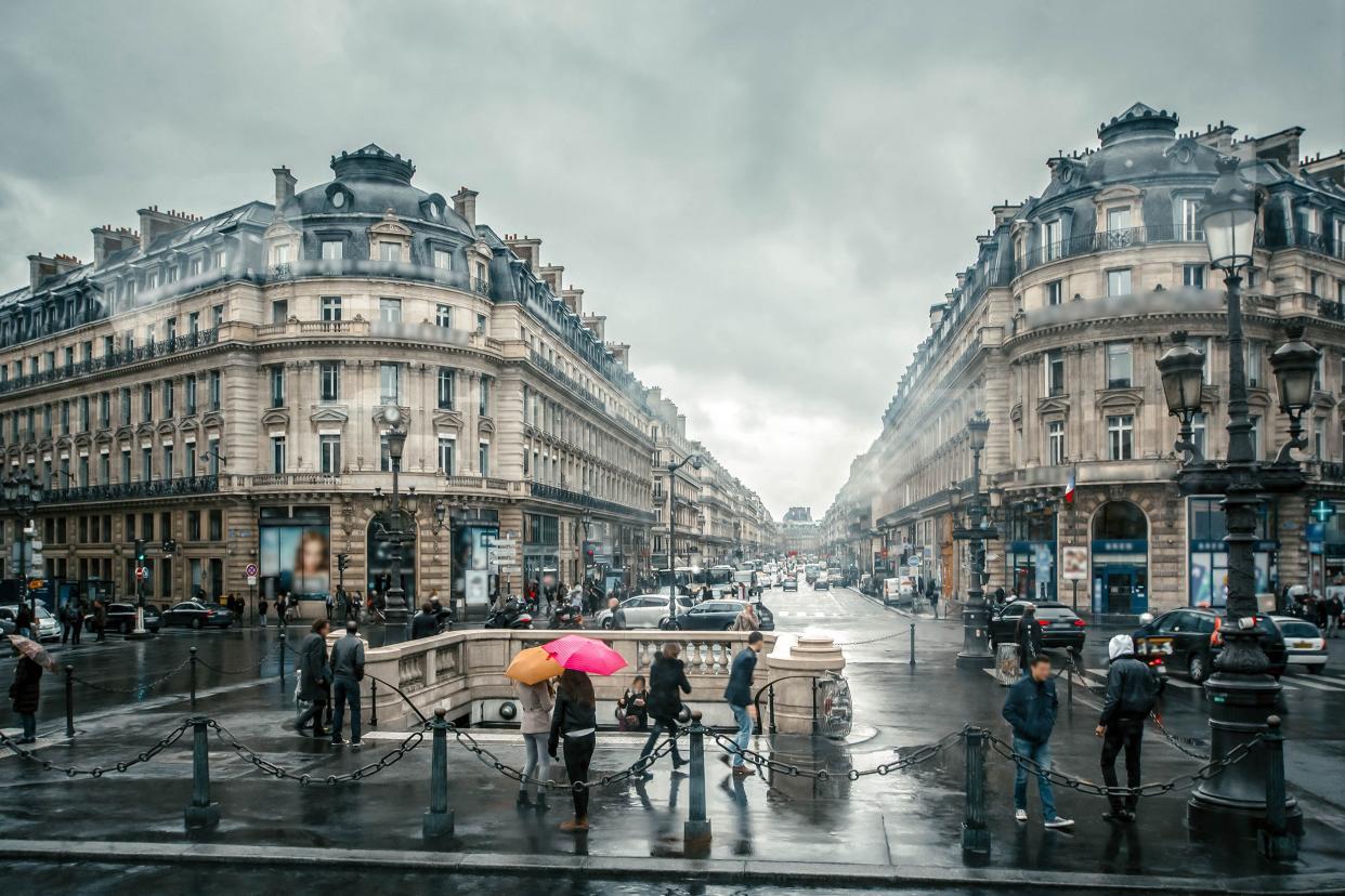 people under colored umbrellas run in the rain on the streets of Paris, France