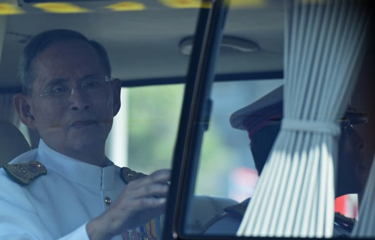 Thai King Bhumibol Adulyadej (L), flanked by his son Crown Prince Maha Vajiralongkorn (R-partly hidden), waves to a crowd of well-wishers as he travels in a motorcade to the Royal Palace