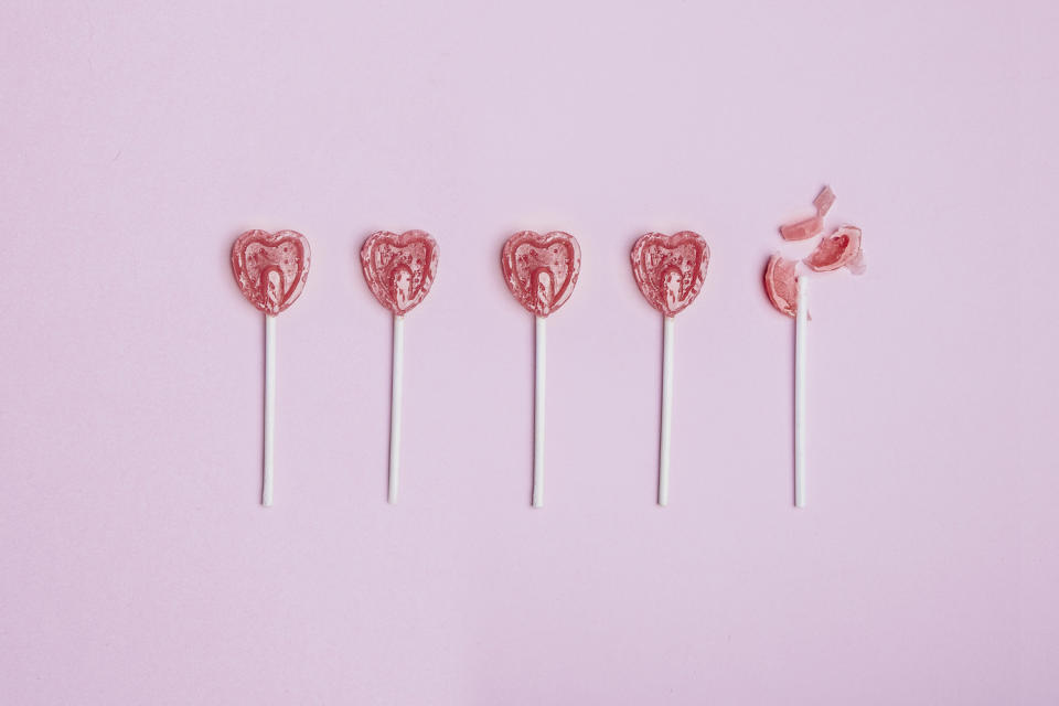 Five lollipop hearts on a pink floor, but the last one is smashed to pieces.