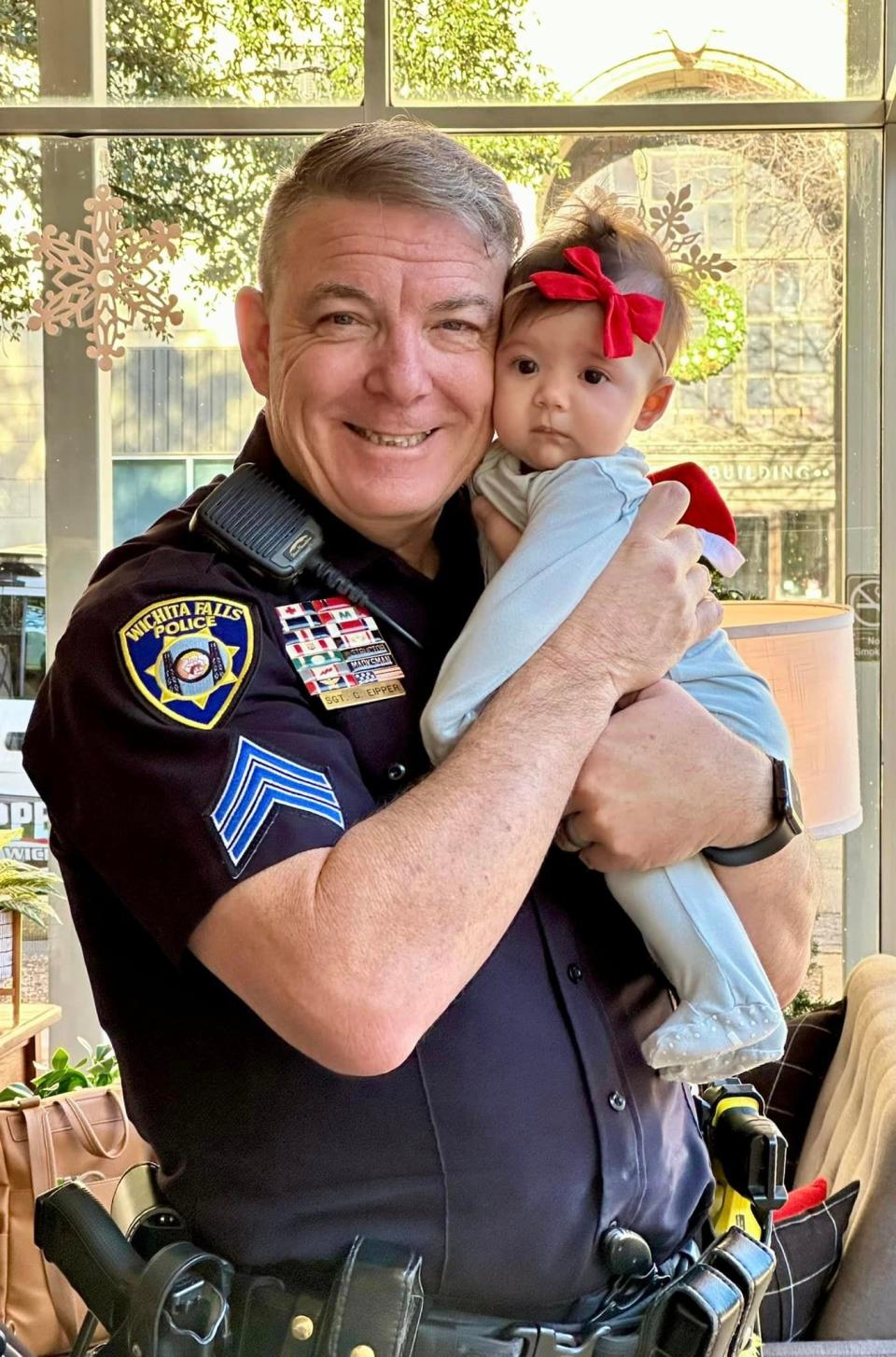 Wichita Falls police Sgt. Charlie Eipper, community services supervisor, holds his seventh grandchild, Emersyn Davis, and her big red bow during a Christmassy Coffee with a Cop event Dec. 16 at 8th Street Coffeehouse downtown. Emersyn is the daughter of Zach and Brianna Davis.