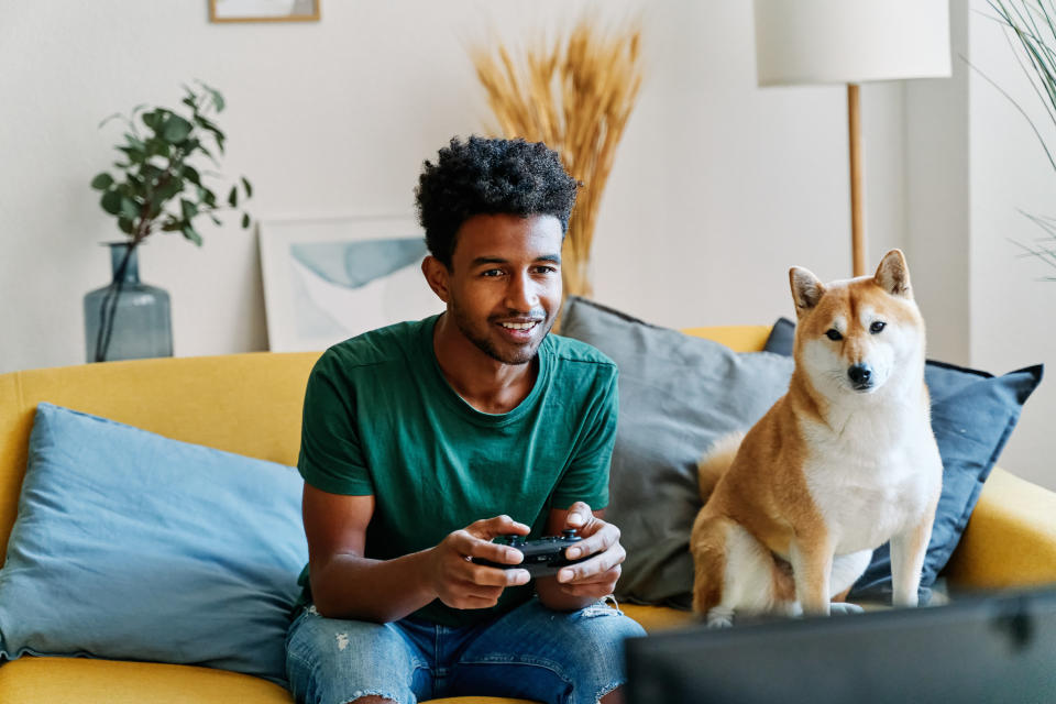 a person playing video games next to their dog