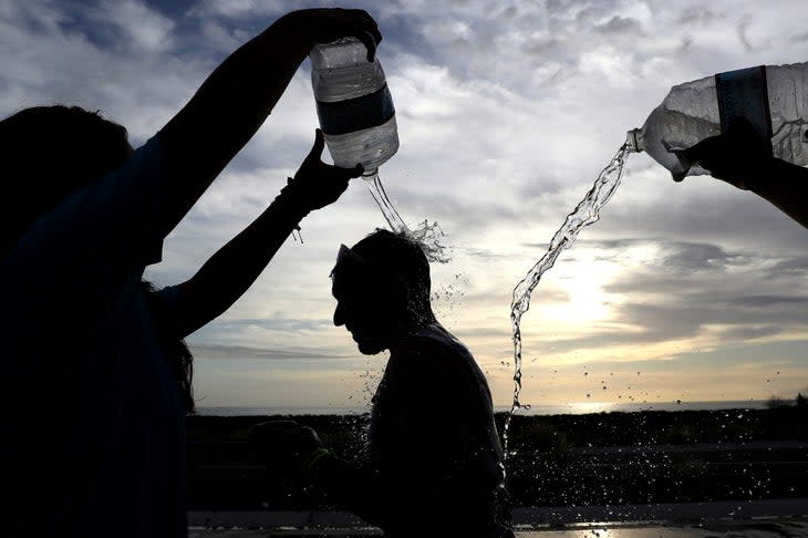 Volunteers pour water over an athlete running through the Ironman Kona Energy Lab