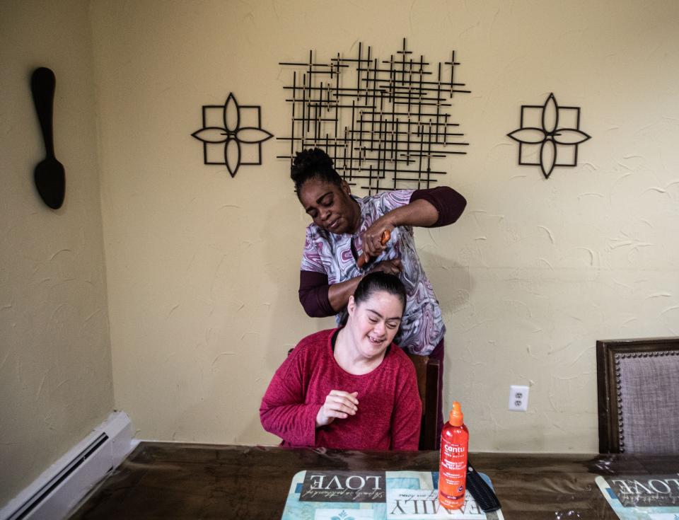 Linda Thompson, a direct support professional, brushes the hair of Jennifer Ojelua at Jawonia's Johansen Home in Monsey, New York. A new report says low wages are contributing to severe staffing shortages at programs for people with disabilities.