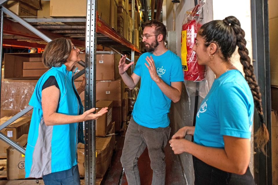 The author, Alex Weisler (center), discusses medical equipment and distribution plans with colleagues at a humanitarian aid warehouse in Modi’in, Israel, part of the organization's emergency response which includes providing hospitals and evacuation centers with equipment for the elderly, people with disabilities, and others in need.