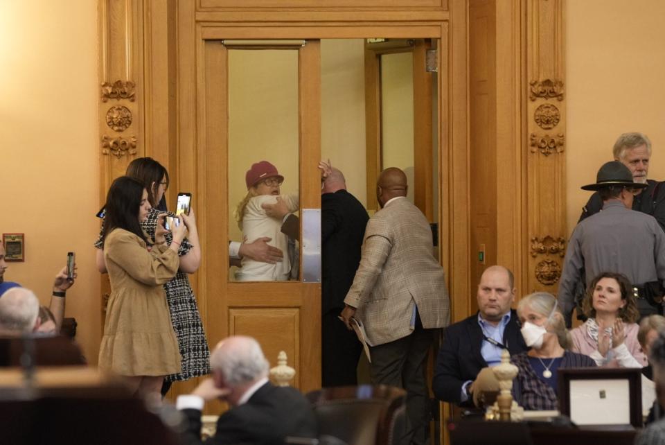 A protester is escorted out of the Ohio Senate chamber on Jan. 24 as lawmakers debate an override of Gov. Mike DeWine's veto of House Bill 68. The bill would restrict health care for transgender minors and prohibit transgender girls from playing on female sports teams.