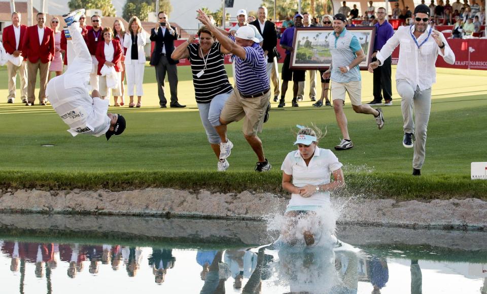 Lexi Thompson jumps into Poppy's Pond after winning the Kraft Nabisco Championship golf tournament Sunday, April 6, 2014, in Rancho Mirage, Calif. (AP Photo/Chris Carlson)