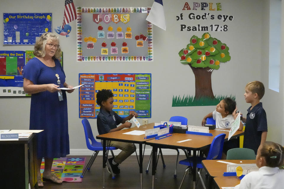 Kindergarten teacher Terrie Osborne helps students in her class at the Winter Garden Christian Academy Thursday, Aug. 29, 2024, in Winter Garden, Fla. (AP Photo/John Raoux)