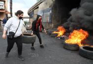 Demonstrators carry a tire to be set on fire during a protest in Zouk