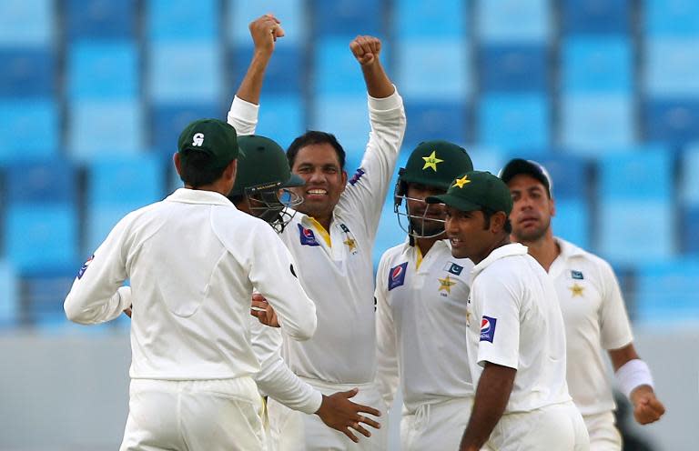 Pakistani bowler Zulfiqar Babar (C) celebrates the dismissal of Australian batsman David Warner during the fourth day of the first test cricket match between Pakistan and Australia in Dubai on October 25, 2014