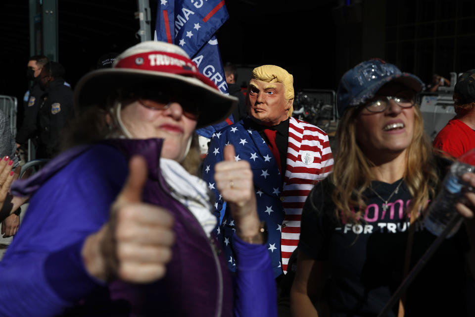 A demonstrator wears a mask of President Donald Trump while standing with others outside the Pennsylvania Convention Center where votes are being counted, Friday, Nov. 6, 2020, in Philadelphia. (AP Photo/Rebecca Blackwell)