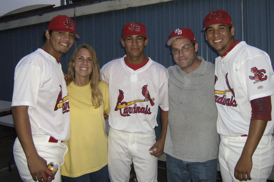 In this photo provided by TeriAnn Reynolds, hosts TeriAnn, second from left, and John Reynolds, second from right, pose with minor league baseball players from Venezuela, Reynier González, left, Eduardo Sánchez, center, and David Peralta, right, at the St. Louis Cardinals minor league baseball team stadium in Johnson City, Tenn., in August 2007. TeriAnn Reynolds and her family were part of a little-known but vital piece of baseball's minor leagues for decades: host families. Players at the lower levels of the minor leagues in places like Johnson City or Lake Elsinore, California, often stayed at the homes of local families instead of apartments or hotels — a way to save money for low-wage players as they transitioned into their lives as pro athletes. (Photo courtesy TeriAnn Reynolds via AP)