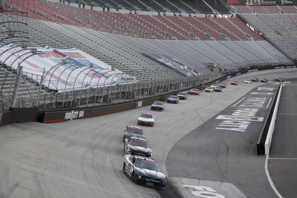 Drivers make their way around the track past empty stands during a NASCAR Xfinity Series auto race at Bristol Motor Speedway Monday, June 1, 2020, in Bristol, Tenn. The race is being run without fans in the stands due to the coronavirus outbreak. (AP Photo/Mark Humphrey)