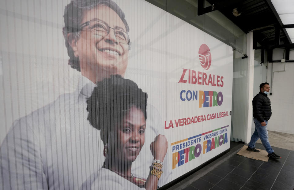 A man walks near a campaign banner of Historical Pact coalition presidential candidate Gustavo Petro and his running mate Francia Marquez, ahead of weekend elections in Bogota, Colombia, Monday, June 13, 2022. Elections are set for June 19. (AP Photo/Fernando Vergara)