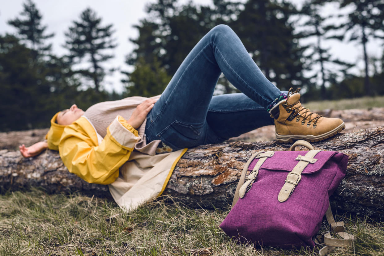 Woman resting on log after hike in mountain