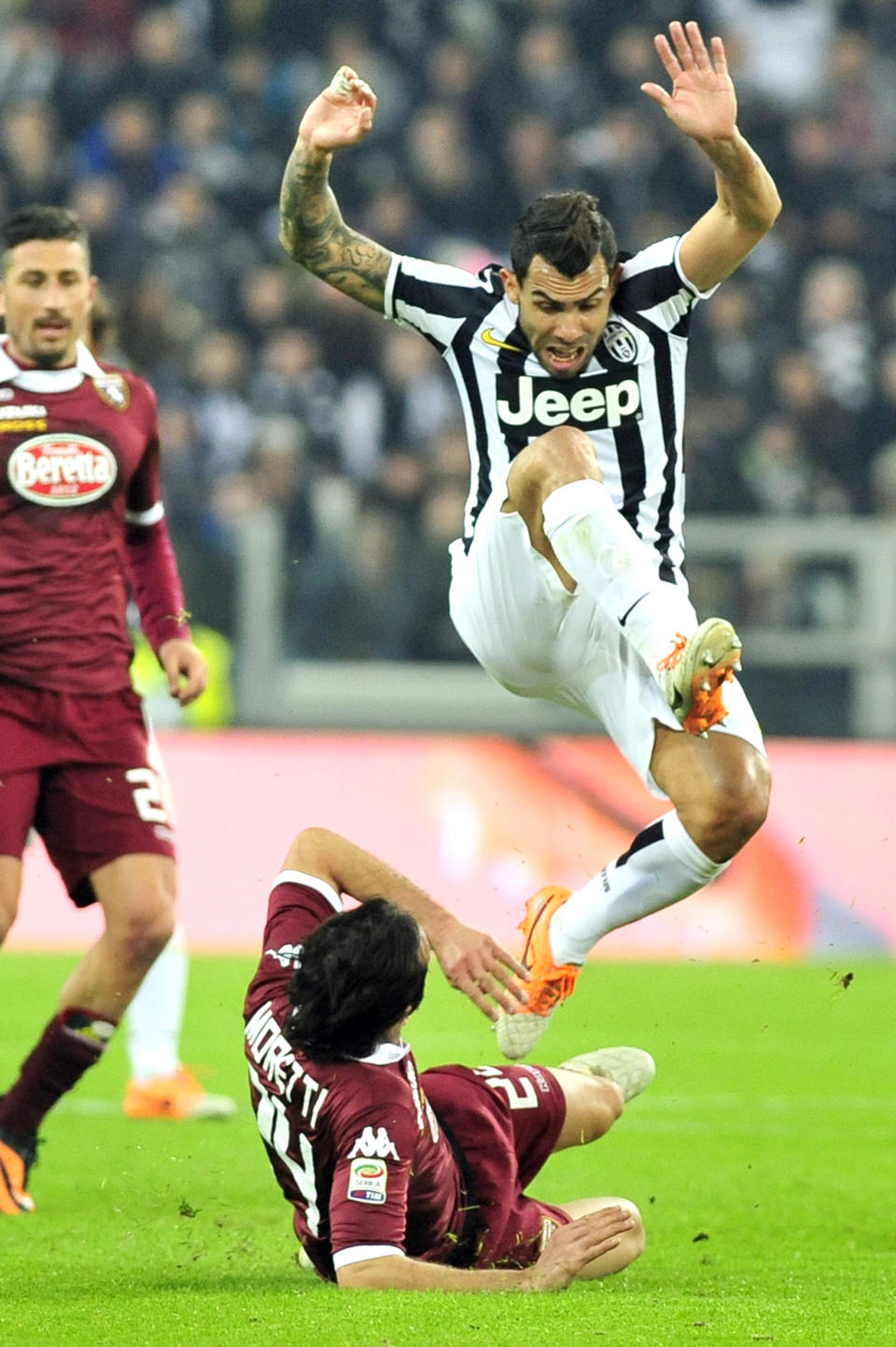 Juventus forward Carlos Tevez, of Argentina, jumps Torino defender Emiliano Moretti during a Serie A soccer match between Juventus and Torino at the Juventus stadium, in Turin, Italy, Sunday, Feb. 23, 2014. (AP Photo/Massimo Pinca)