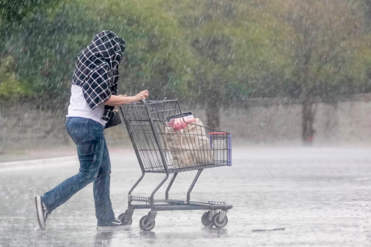 A woman pushes her cart in the rain after shopping at H-E-B Escarpment Village in Southwest Austin on March 27.