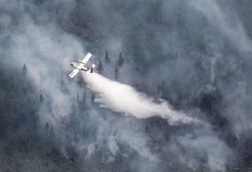 An Aircraft drops water scooped from nearby Sand Lake onto the Greenwood Fire , about 50 miles north of Duluth, Minn., Tuesday, Aug. 17, 2021, as seen from an airplane above the temporary flight restriction zone. (Alex Korman/Star Tribune via AP)