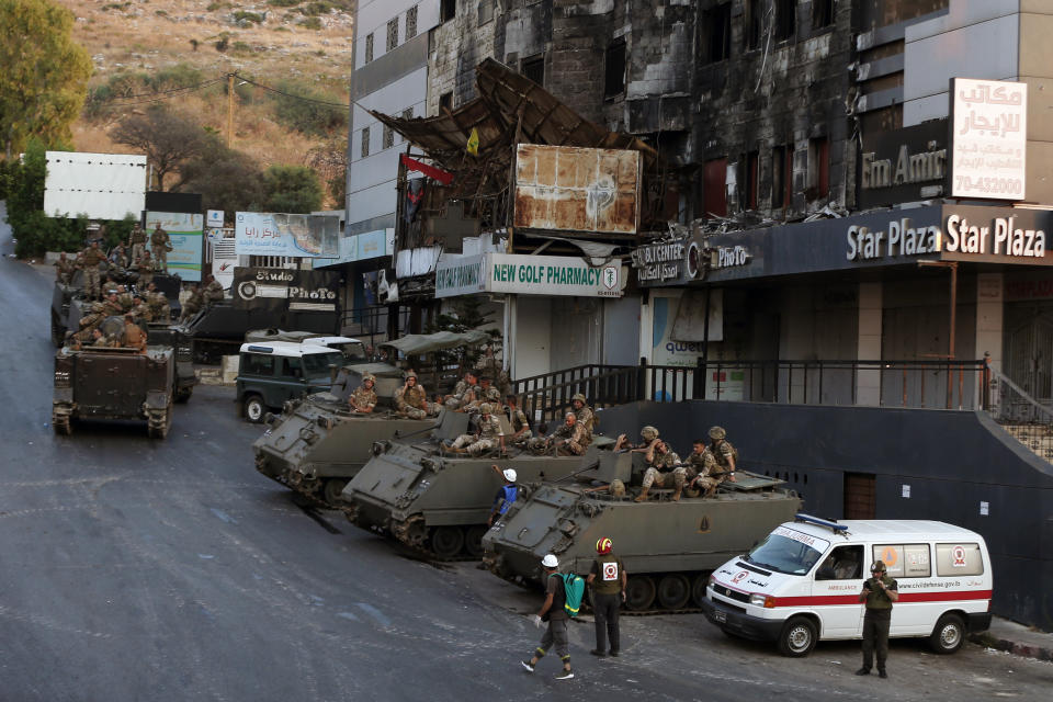 Lebanese army soldiers sit on their armored vehicles as they deployed to contain the tension after heavy fire in the coastal town of Khaldeh, south of Beirut, Lebanon, Sunday, Aug. 1, 2021. At least two people were killed on Sunday south of the Lebanese capital when gunmen opened fire at the funeral of a Hezbollah commander who was killed a day earlier, an official from the group said. (AP Photo/Bilal Hussein)