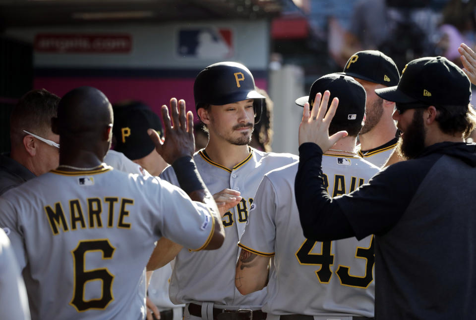 Pittsburgh Pirates' Bryan Reynolds, center, is greeted in the dugout after scoring on a single from Melky Cabrera during the first inning of the team's baseball game against the Los Angeles Angels on Wednesday, Aug. 14, 2019, in Anaheim, Calif. (AP Photo/Marcio Jose Sanchez)