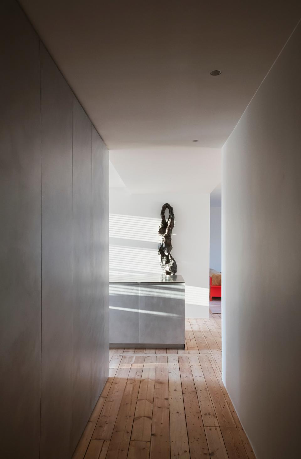 In the entry hall, as throughout the apartment, Thulstrup stripped the existing pine floors and installed brushed-aluminum storage from his modular system for Reform; the wall-mounted artwork is by Carl Emil Jacobsen.