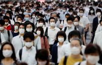 FILE PHOTO: People wearing protective masks amid the coronavirus disease (COVID-19) outbreak, make their way during rush hour at a railway station in Tokyo