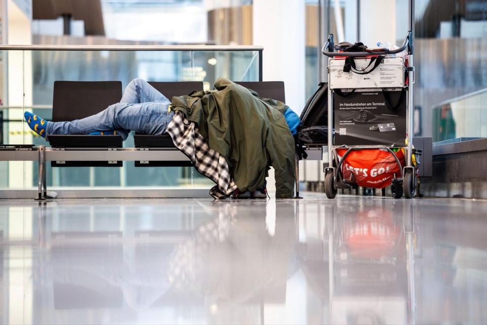 A person sleeps on a bench in the departure hall at Munich Airport (AP)