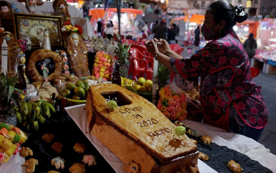 Lourdes Vasquez arranges a coffin-shaped bread and other offerings at an altar set up in honour of the victims of the coronavirus disease at a market before Day of the Dead celebrations, in La Paz, Bolivia -  DAVID MERCADO / REUTERS