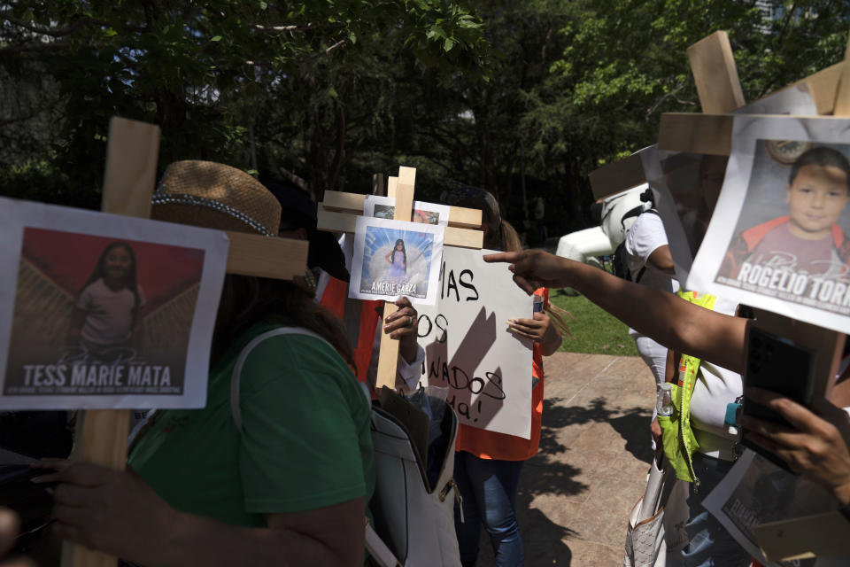 Protesters carry crosses with photos of victims of the Robb Elementary School shooting in Uvalde, Texas, as they demonstrate outside the George R. Brown Convention Center where the National Rifle Association's annual meeting is held in Houston, Friday, May 27, 2022. (AP Photo/Jae C. Hong)