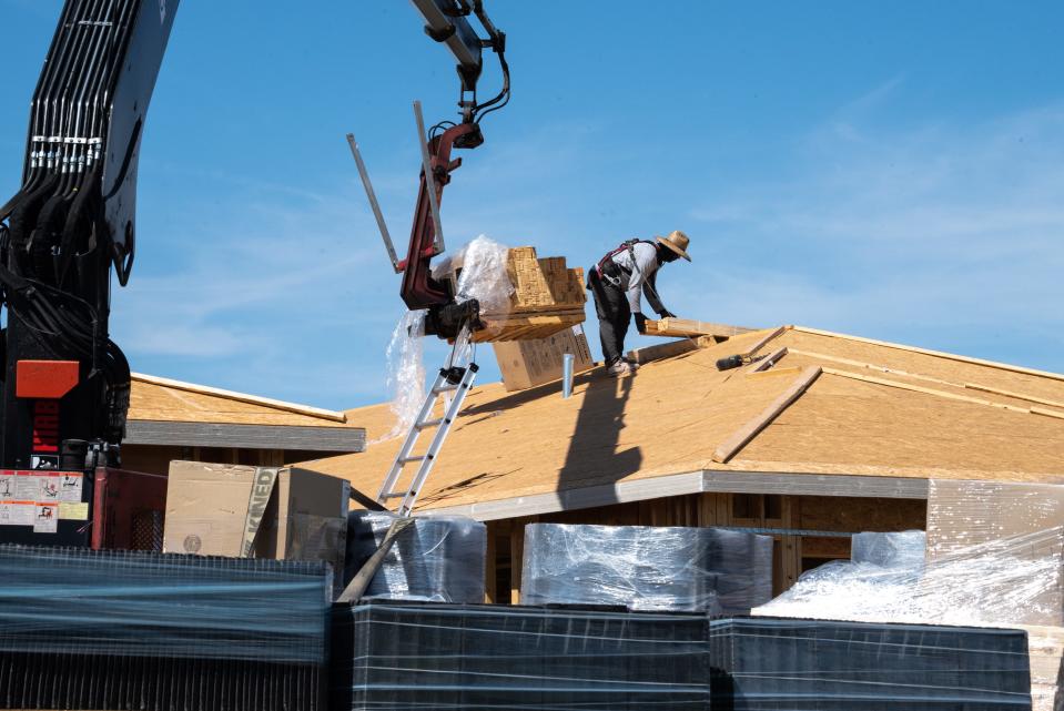 Howard Rodriguez unloads material on the roof of a new home under construction, July 17, 2023, in Eastmark, Mesa.