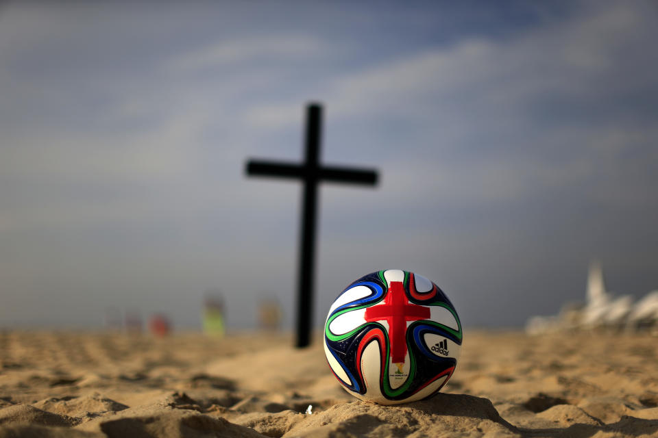 The 2014 World Cup official soccer ball, called Brazuca, painted by protesters with a red cross and placed in front a cross, forms part of a tribute to children who have died from stray bullets during police operations, on Copacabana beach in Rio de Janeiro, Brazil, Wednesday, May 7, 2014. Organized by Rio de Paz, protesters say the money spent on World Cup preparations should have been used for the development of better schools, health care and improved security in shantytowns. (AP Photo/Hassan Ammar)