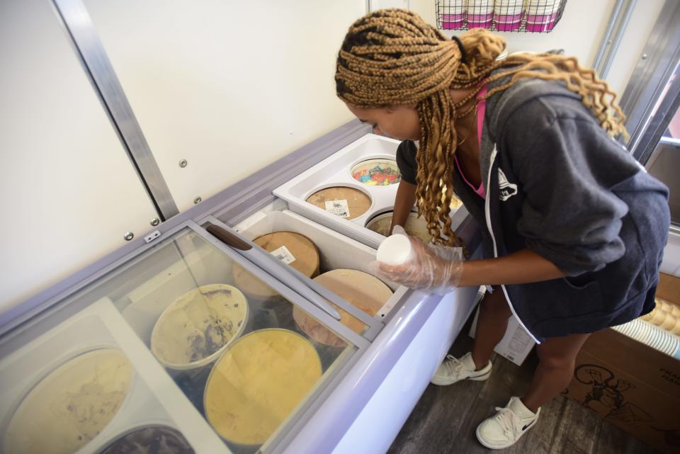 Here's The Scoop employee Makayla Rice scoops a serving of ice cream for a customer outside the new ice cream truck parked on the waterfront along Thomas Edison Parkway on Friday, July 29, 2022.